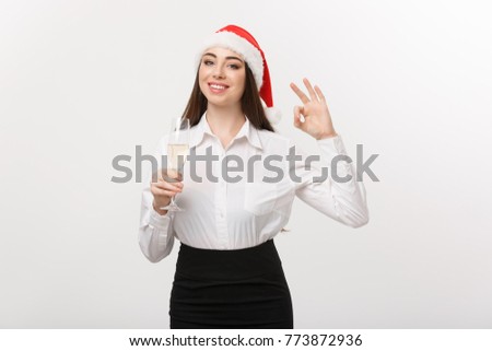 Christmas Celebration - Young beautiful business woman celebrating christmas with glass of champagne and showing ok sign. 