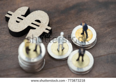 Miniature people: business man making decision on world map in front of wooden dollar sign and coins stacks, success, dealing, greeting and partner concept. Flat lay
