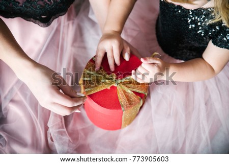 mother with daughter unpacking gift box hands close up