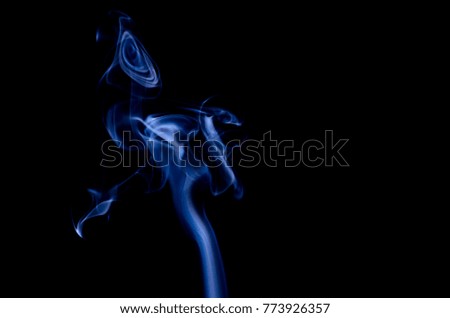 Incense stick are burning on the black background. The smoke of incense