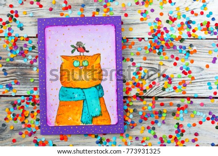 Watercolor card (postcards) with funny cat and a bird on his head on white wooden background with multicolored confetti. Top view.