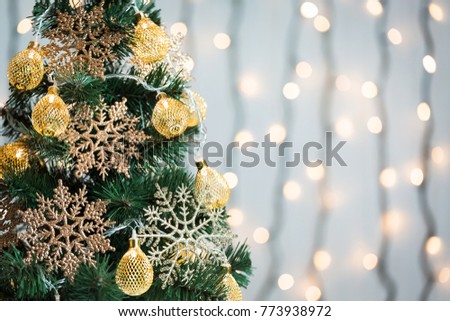 A Christmas tree decorated with snowflakes and a garland on the background of a bokeh and white boards. Merry Christmas, ideas for postcards for winter holidays