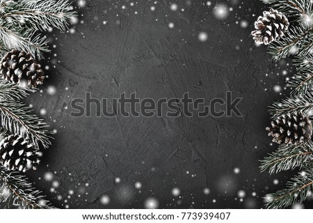 Xmas theme with fir branches, evergreen pines, on snowy black, stone background viewed from above, greeting card with space for text Royalty-Free Stock Photo #773939407