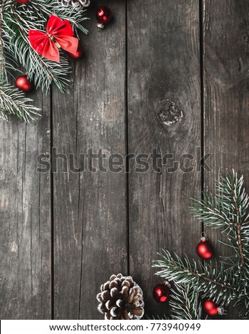 Vertical Christmas theme with fir branches, red bows and globes, cones, on rustic dark wooden background viewed from above, top, greeting card with space for text Royalty-Free Stock Photo #773940949