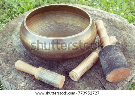 Tibetan Singing  bowl with mallets on a wooden backgroung. Asian traditional theme. Photo with color toning.