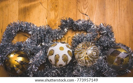 The wide picture of the silver and gold Christmas decorations on the old wooden desk