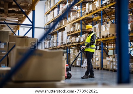 Male warehouse worker pulling a pallet truck. Royalty-Free Stock Photo #773962021