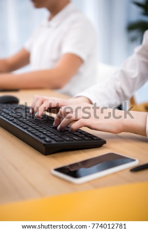 cropped image of students typing on keyboards