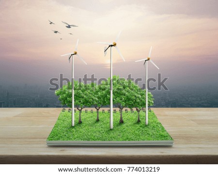 Wind turbines, trees, grass and birds from an open book on wooden table over city tower at sunset, vintage style, Ecological concept