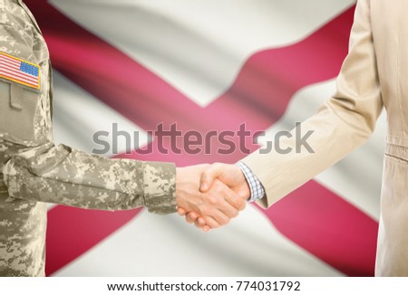 American soldier in uniform and civil man in suit shaking hands with USA state flag on background - Alabama