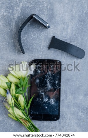 A broken phone with flowers close-up on a stone background. View from above