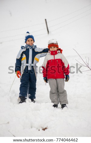 Playful cheerful children sledding and making snowman in snow
