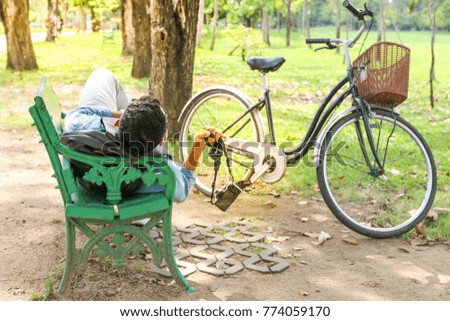 A man or tourist sleep or sitting on green chair with hands up hold the camera as relax time in a public park concept
