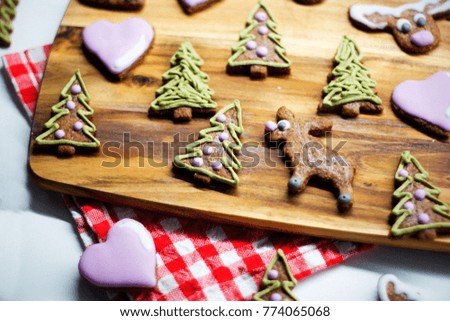 Small pieces of traditional czech christmas cookie gingerbread - reindeer, christmas tree, gingerbread man on wooden tray decorated by red checked cloth