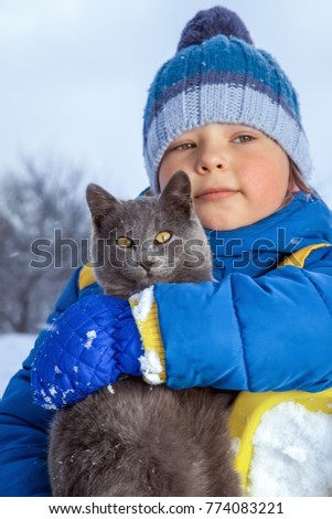 boy plays with a cat outdoors in winter (focus on cat)