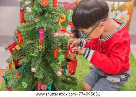 Boys wearing red shirts, wearing glasses, decorating Christmas trees To celebrate the annual Christmas festival Chiang Rai Province, Thailand