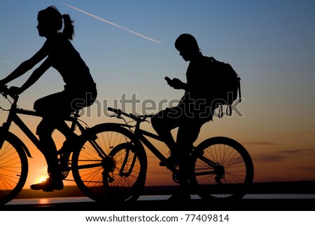 Couple bicycler  ride on sunset and call by phone