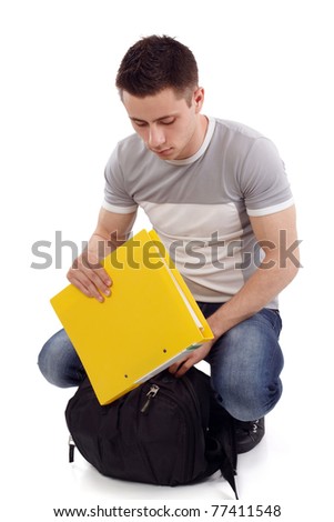 Young student packing his yellow notebook going back to school