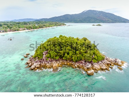 View from above of a small isolated tropical island on a shallow water near Lipe island in a blur background of an island on the horizon, in the Andaman sea, Satoon, Thailand