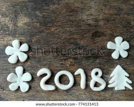 Beautiful wallpaper with number year 2018 ,Christmas tree and white flowers are made from clay plasticine placed on dark wooden background,festival dough
