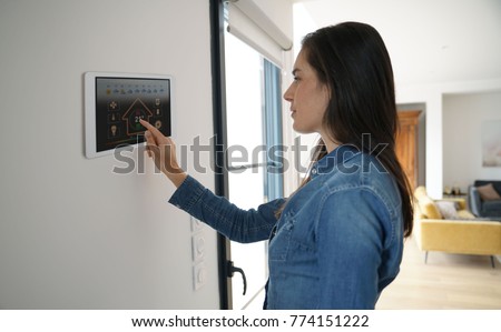 Woman using smart wall home control system  Royalty-Free Stock Photo #774151222