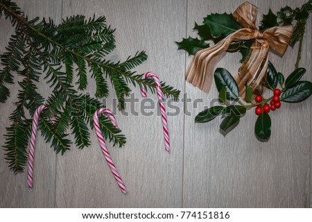 Candy cane christmas decoration with holly and pine tree and gold bow with wooden background