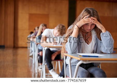 Anxious Teenage Student Sitting Examination In School Hall Royalty-Free Stock Photo #774167659