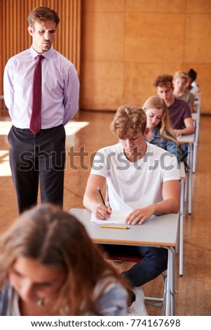 Teenage Students Sitting Examination With Teacher Invigilating Royalty-Free Stock Photo #774167698