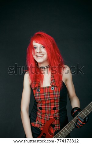 Funny redhead rock girl with red bass guitar over dark background