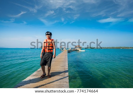 Asian man with snorkeling mask walking on the wooded bridge to the harbor in Koh Mak, Koh Mak and Kood is island and sea in Thailand
