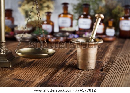 Natural medicine background. Brass mortar, scale. Rustic table. Assorted dry herbs in bowls. Bokeh.