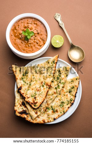 Dal makhani or daal makhni is a popular food from Punjab / India made using  whole black lentil, red kidney beans, butter and cream and served with garlic naan or Indian bread or roti Royalty-Free Stock Photo #774185155