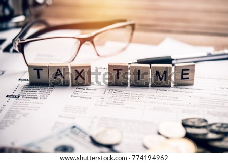 Tax time concept with wooden blocks and office tools on tax form background