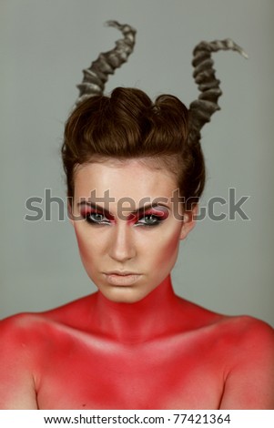 Woman with horns on her head, body painted red. Makeup for Halloween