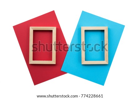 The twin of vertical blank wooden picture frame on blue and red paper. Isolated background