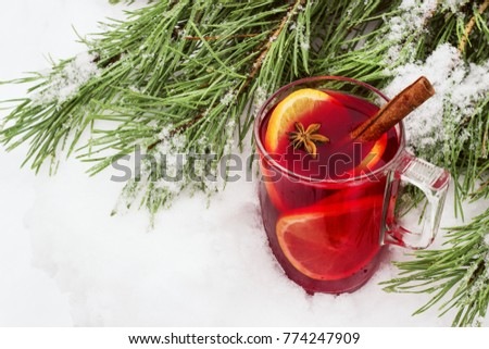 mulled wine on the street in the snow with a branch of pine.