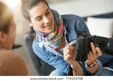 Photographer showing pictures to model on camera screen