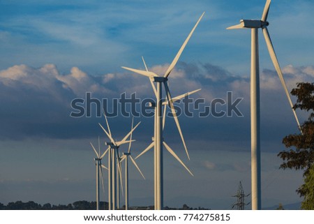 Wind turbine on mountain with blue sky background at sunset.