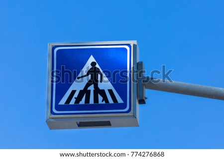 Blue-white road sign pedestrian crossing against the sky