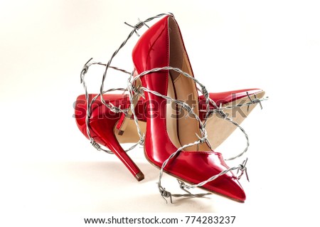 Uncomfortable shoes, sexism in fashion and foot pain concept with high heel stilettos wrapped in barbed wire representing the aches and pains caused to your feet by poorly constructed footwear Royalty-Free Stock Photo #774283237