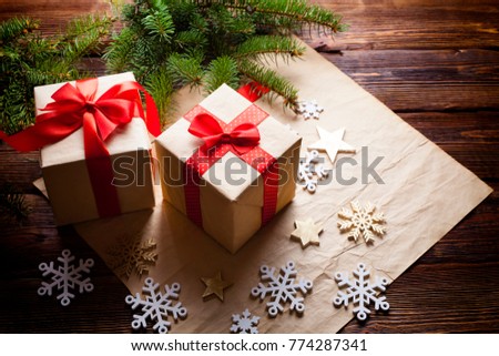 Two Christmas gifts and decorations on paper and wooden background