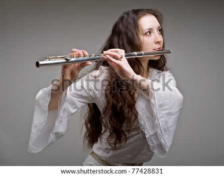 girl plays the flute on a grey background