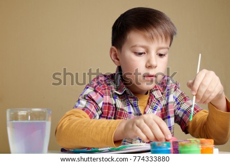 Caucasian boy is painting with watercolors.
