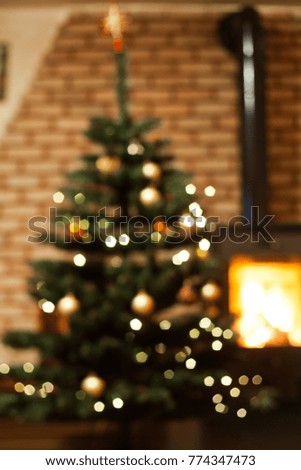 blurred photo of room with christmas tree and fire burning in fireplace