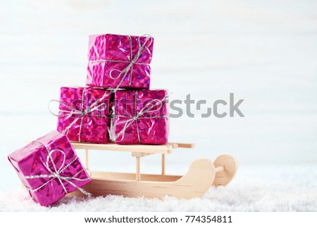 Wooden toy sleigh with gift boxes on white table
