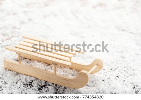 Wooden toy sleigh on white snow