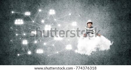 Young little boy keeping eyes closed and looking concentrated while meditating on flying cloud in the air with social network structure on gray dark wall on background.