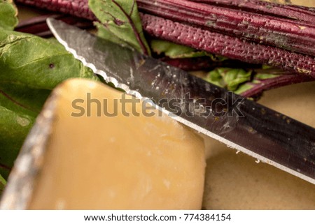 Food picture of parmigiana cheese, beets, Artichokes, grinders and knife on a platter for food preparation.