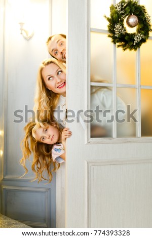 Picture of couple with daughter peeking out from behind door with Christmas wreath