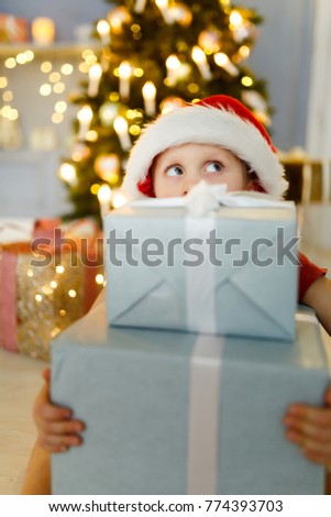 New Year's image of boy in santa hat with gift box on background